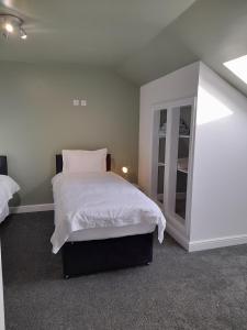 1 dormitorio con cama blanca y espejo en Coastal Millennium Apartment, en Llanelli
