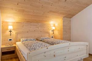 1 dormitorio con 1 cama con pared de madera en Appartamento Confolia 2, en La Valle
