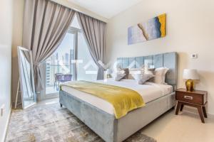 a bedroom with a bed and a large window at Staycae Holiday Homes - Reva in Dubai