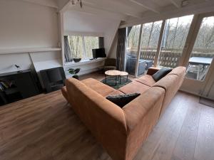 una sala de estar con un gran sofá marrón en una habitación en Bos Chalet Durbuy, en Durbuy