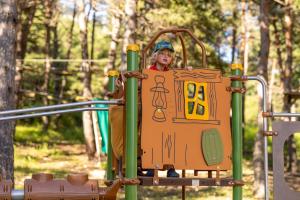 un niño pequeño está jugando en un parque infantil en Camping RCN Les Collines de Castellane, en Castellane