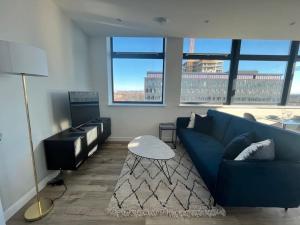 a living room with a blue couch and a table at Brand new modern 1 bed apartment near Old Trafford Stadium in Manchester