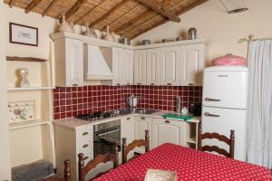 uma cozinha com armários brancos e uma mesa com uma toalha de mesa vermelha em Beautiful house in Orosei em Orosei