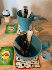 niebieski kubek i spodek z zestawem do parzenia herbaty na stole w obiekcie Le JOËL appartement F1 de 21 m² w mieście Choisey