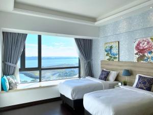 a bedroom with two beds and a large window at R&F Princess Cove JB Apartment Suites By SC Homestay in Johor Bahru