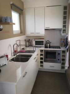 Una cocina con gabinetes blancos y un fregadero. en «  Le Sand-Wedge » appartement vue mer, en Wimereux