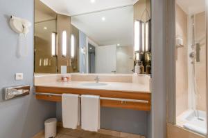 uma casa de banho com um lavatório e um espelho grande em Holiday Inn Nice - Port St Laurent, an IHG Hotel em Saint-Laurent-du-Var