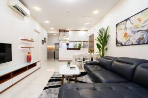 ein Wohnzimmer mit einem schwarzen Ledersofa und einem Tisch in der Unterkunft Jessie Apartment - Infinity pool - Masteri Millennium in Ho-Chi-Minh-Stadt