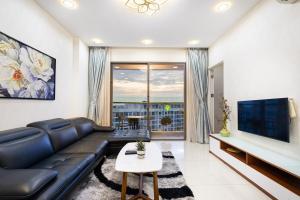ein Wohnzimmer mit einem schwarzen Ledersofa und einem TV in der Unterkunft Jessie Apartment - Infinity pool - Masteri Millennium in Ho-Chi-Minh-Stadt