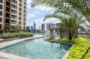 einen Pool mit einer Palme und Gebäuden in der Unterkunft Jessie Apartment - Infinity pool - Masteri Millennium in Ho-Chi-Minh-Stadt