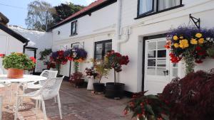 a patio with a table and chairs and flowers at Cider Cottage in Sidmouth
