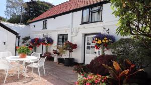 a white house with a table and chairs and flowers at Cider Cottage in Sidmouth