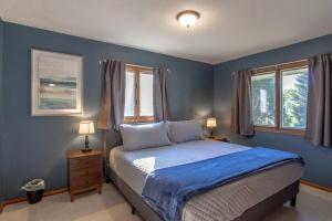 a blue bedroom with a bed and two windows at Family Home W/ 2 King, 2 Queen Beds + Game Room in Bemidji