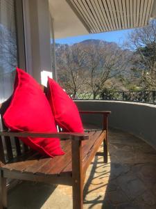 Cape Town的住宿－Authentic Newlands，门廊上两个红色枕头坐在长凳上