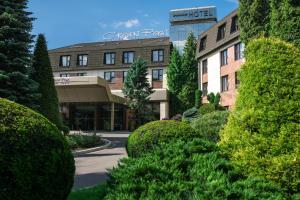 a view of a building with bushes and a street at Booking Hotel Crown Piast & Spa in Kraków