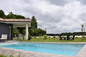 a swimming pool with chairs and a gazebo at L'Acacia in Bénesse-Maremne