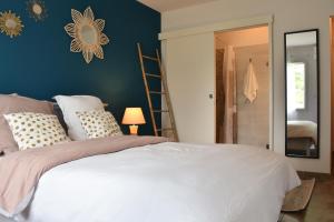 a bedroom with a white bed and a blue wall at L'Acacia in Bénesse-Maremne