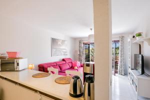a kitchen and living room with a pink couch at 10A Amarilla Bay Pool Smart TV WI FI in Costa Del Silencio