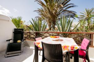 a table and chairs on a balcony with palm trees at 10A Amarilla Bay Pool Smart TV WI FI in Costa Del Silencio