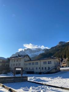 a building in the snow with mountains in the background at Soggiorno Dolomiti in Mazzin