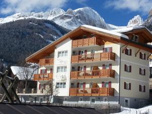 a hotel with snow covered mountains in the background at Residence Ciasa Alpe in Vigo di Fassa