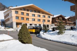 un autobús amarillo está estacionado frente a un edificio en Gstaad Saanenland Youth Hostel, en Gstaad