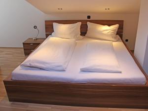 ein großes Bett mit weißer Bettwäsche und Kissen in der Unterkunft Ferienwohnung Kohlstatt in Kiefersfelden