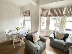 a living room with a table and a couch and chairs at Merrifield House in Sidmouth