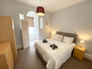 sypialnia z białym łóżkiem z dwoma czarnymi przedmiotami w obiekcie Merrifield House w mieście Sidmouth