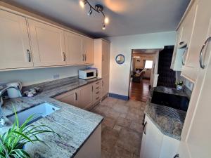 a kitchen with white cabinets and a sink at Longtail Cottage in Sidmouth