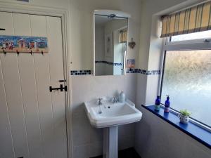 ein Badezimmer mit Waschbecken und Spiegel in der Unterkunft Longtail Cottage in Sidmouth + 22 Fotos