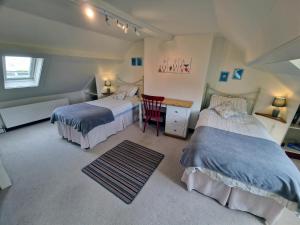 a bedroom with two beds and a desk with a chair at Longtail Cottage in Sidmouth