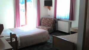 a hotel room with a bed and a chair at B&B Chiara- Alleghe in Alleghe