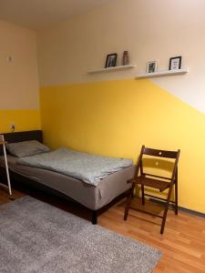 a bedroom with a bed and a chair and a yellow wall at W Rynku in Wrocław