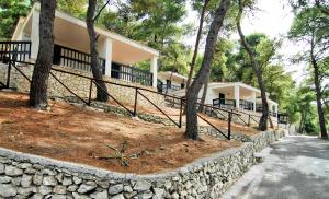 a house with a stone retaining wall and trees at Gattarella Family Resort - Self catering accommodations in the pinewood in Vieste