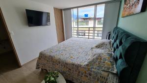 a bedroom with a bed and a large window at Hermoso Apartamento Entero - Parqueadero - Pino in Ibagué