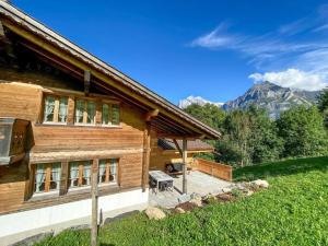 a wooden house with a patio and mountains in the background at Ferienhaus Chalet Simeli in Grindelwald
