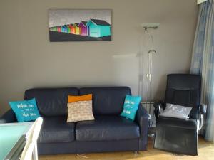 ein Wohnzimmer mit einer schwarzen Couch und einem Sessel in der Unterkunft Cosy, zuidgerichte studio in De Panne met WiFi in De Panne