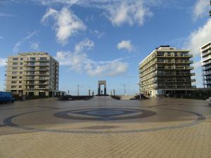 einen großen Innenhof mit zwei hohen Gebäuden und einer Uhr in der Unterkunft Cosy, zuidgerichte studio in De Panne met WiFi in De Panne