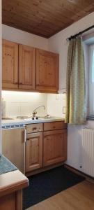 cocina con armarios de madera, fregadero y ventana en Ferienhaus Lechtaler Alpen, en Bach