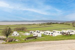 eine Gruppe von Wohnmobilen auf einem Feld neben dem Wasser in der Unterkunft Ivy Cottage with Hot tub! in Silverdale