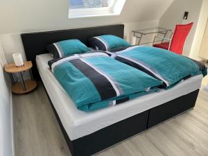 Una cama con edredón azul y almohadas. en Waldblick, en Herford