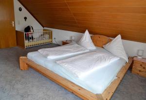a wooden bed with white sheets and a dog in a room at Ferienwohnung Landzettel in Amorbach