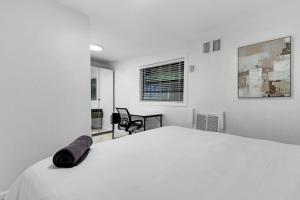 een witte slaapkamer met een bed en een stoel bij Private King Size One Bedroom Apartment with Laundry in Miami