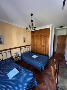 two beds in a room with blue checked sheets at Casa Kini in Cazalla de la Sierra