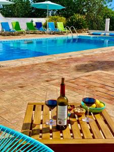 a bottle of wine and two glasses on a table by a pool at The Lemon Tree Villa in Moncarapacho