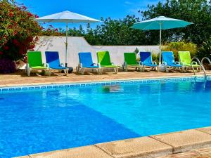 a group of chairs and umbrellas next to a swimming pool at The Lemon Tree Villa in Moncarapacho