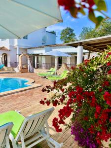 a house with a swimming pool and some red flowers at The Lemon Tree Villa in Moncarapacho