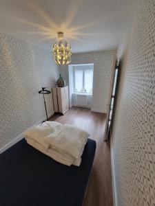 sypialnia z łóżkiem i żyrandolem w obiekcie Petite maison 40M² à PAIMPONT (35) w mieście Paimpont