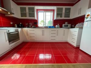a red kitchen with white cabinets and a red tile floor at MyHome in São Roque do Pico
